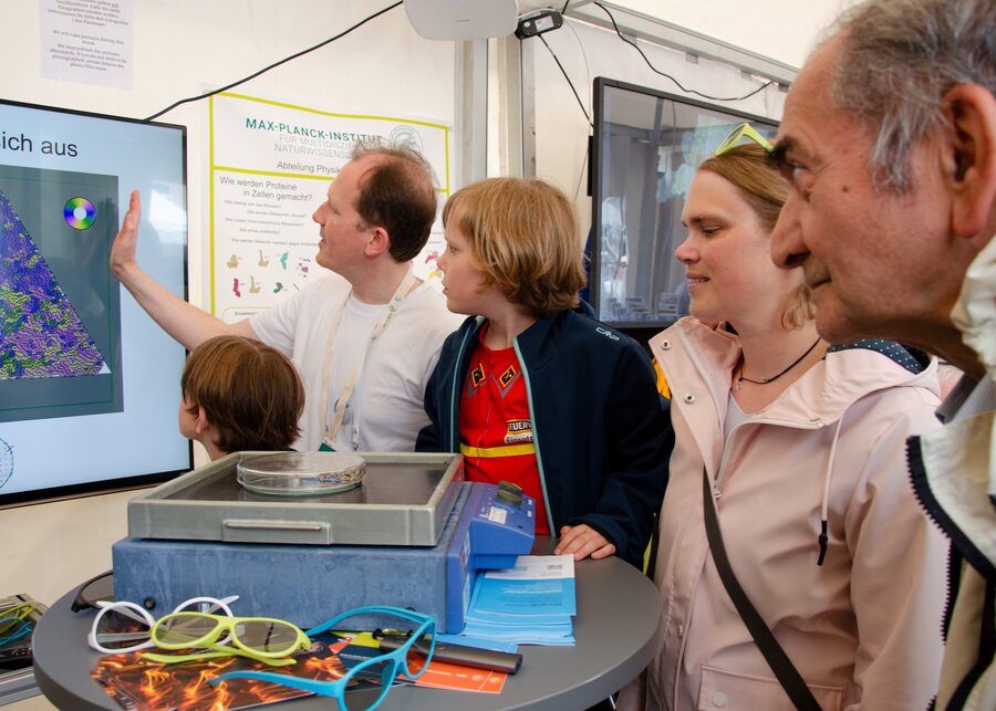 Visitors at the group's outreach booth with 3D glasses and a simulation on screen